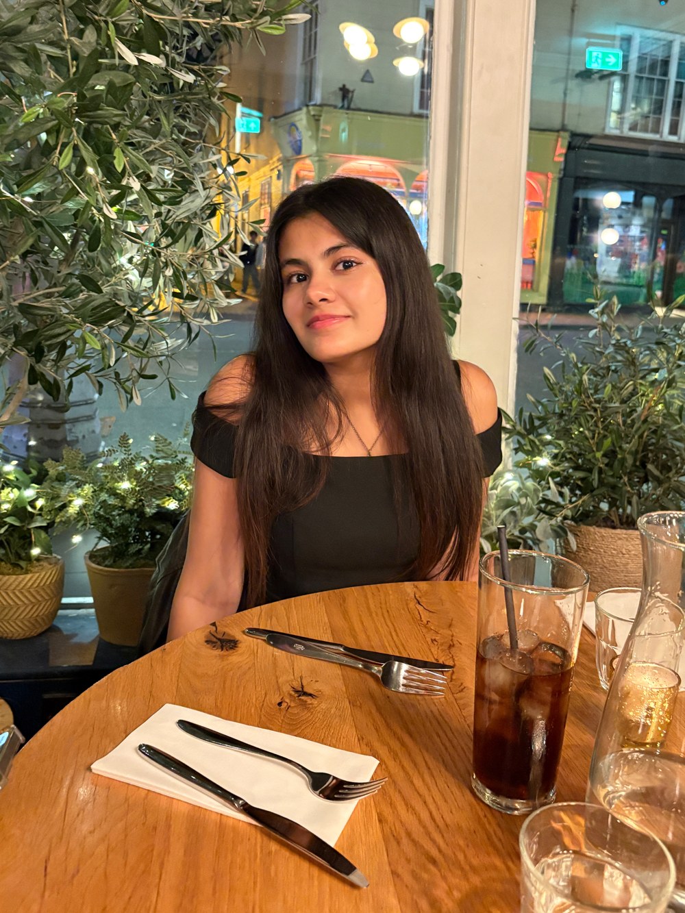 Dhvani (Vee) Shah smiling at a restaurant table by a window